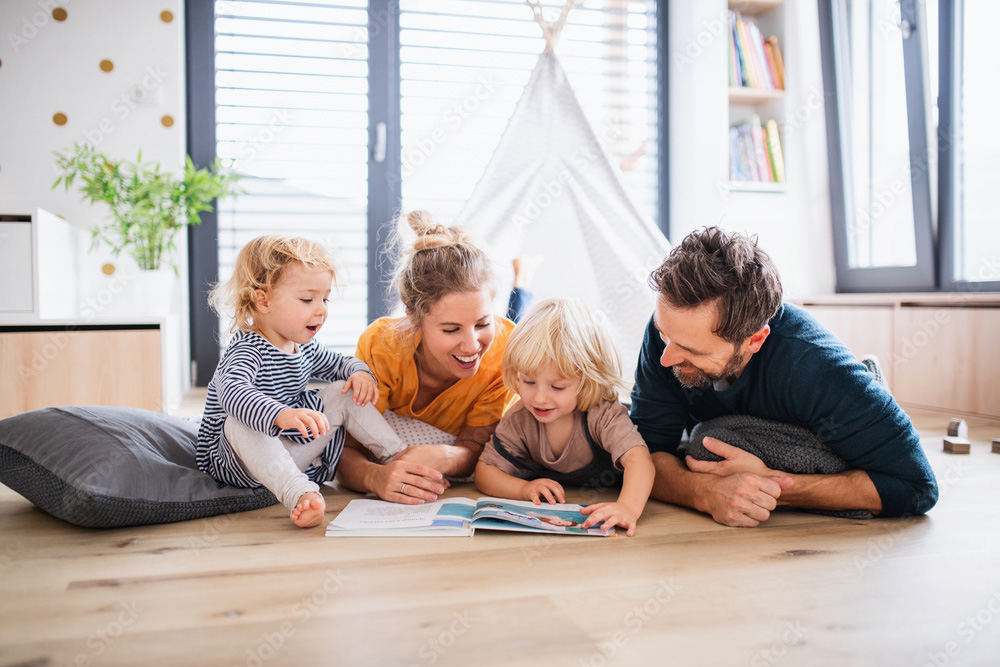 Famiglia felice sta giocando distesa sul pavimento in parquet